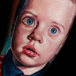 Фото татуировки с изображением лица ребенка с большими голубыми глазами, выполненной в ярком и реалистичном стиле на руке.
