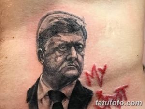 Фото тату портрета Джона Кеннеди с красными брызгами краски, выполненное в реалистичном стиле на плече.