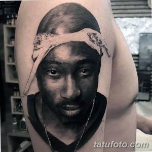 Фото тату: реалистичный портрет 2Pac с банданой на голове на предплечье. Черно-белая татуировка с высокой детализацией и реалистичным изображением лица.