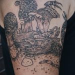 Фото тату на плече с изображением лесного пейзажа, включающего грибы, деревья, насекомых и другие детали, выполненное в технике графики.