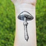 Фото тату на запястье с изображением одного гриба. Черно-белый рисунок с четкими контурами.