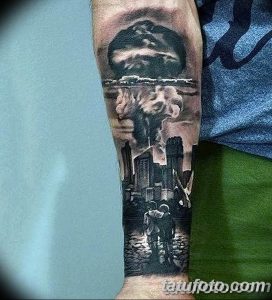 Фото тату на руке, изображающее ядерный взрыв над городом. Детализированный рисунок татуировки в стиле реализм с использованием черно-серых тонов.