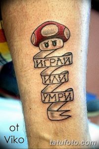 Фото тату персонажа Марио из игры Super Mario с надписями 'Играй', 'Или', 'Умри' на ноге. Рисунок татуировки выполнен в черном цвете.