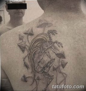 Фото татуировки на спине с изображением грибного леса. Рисунок выполнен в стиле реализм с использованием серых тонов.