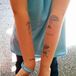 Фото тату с изображением двух маленьких фей на лодыжках. Рисунок выполнен в ярких цветах с использованием тонких линий.