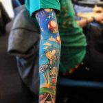 Фото татуировки на руке с персонажами и элементами из игры Super Mario. Рисунок выполнен в ярких, насыщенных цветах с использованием техник штриховки и контурной обводки.