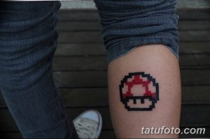 Фотография пиксельной татуировки на ноге с изображением гриба из игры Super Mario. Простой и стильный рисунок татуировки в стиле 8-bit.