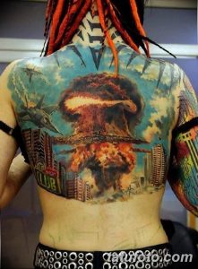 Фотография масштабной татуировки на спине с изображением разрушенного города и взрыва. Детализированный рисунок татуировки в стиле реализм.