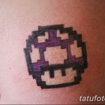 Фото тату с изображением пиксельного блока из игры Minecraft на руке. Татуировка выполнена в черно-фиолетовом цвете, с использованием характерных для игры пикселей.