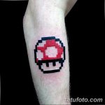 Фото татуировки в стиле пиксель-арт с изображением гриба Super Mushroom из игры Super Mario Bros. Татуировка выполнена в красном и белом цветах.