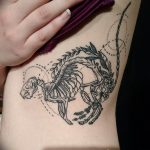 Фото тату: изящный рисунок скелета кошки, украшенного цветами, выполненный на боку. Детальный эскиз для любителей кошек и готической эстетики.