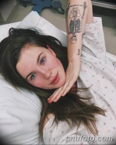 Фото тату: изящный рисунок скелета, обвивающего руку девушки, с добавлением надписей и декоративных элементов.