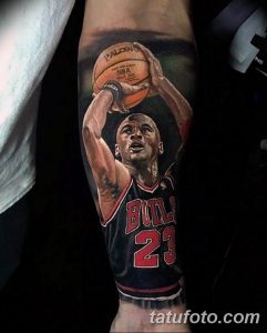 Фото тату с изображением Майкла Джордана в форме Chicago Bulls, держащего баскетбольный мяч. Реалистичный портрет на предплечье.