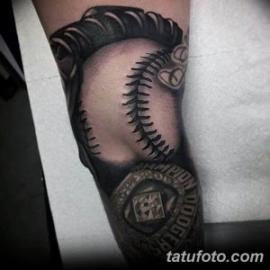 Фото тату на руке с изображением бейсбольного мяча, чемпионского перстня и деталей, связанных с бейсболом. Детализированный рисунок татуировки.