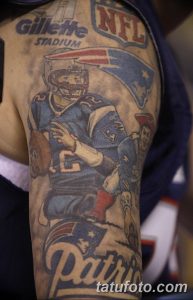 Фото тату на руке с изображением игрока в американский футбол, логотипов NFL и стадиона Gillette Stadium. Детализированный рисунок татуировки.