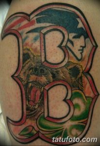 Фото тату на руке с изображением буквы 'B' и головы медведя. Яркий рисунок с использованием различных цветов.