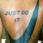 Фото тату на спине: надпись 'Just Do It' и логотип Nike, выполненное в синем цвете.