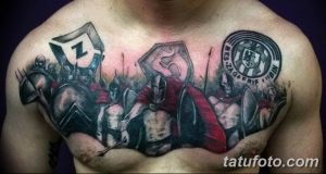 Фото тату на груди: батальная сцена с изображением спартанских воинов в доспехах и с оружием. Реалистичный рисунок татуировки в историческом стиле.
