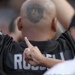 Фото тату большого логотипа команды Raiders, выполненного на лысой голове мужчины.