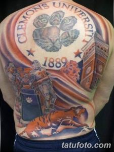 Фото тату на спине с изображением логотипа Clemson University, тигра и архитектурного элемента. Рисунок выполнен в оранжево-синих тонах.
