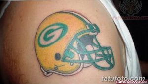 Фото тату на плече с изображением шлема игрока в американский футбол команды Green Bay Packers. Рисунок выполнен в ярких цветах.