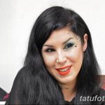 Портрет женщины с черными волосами и татуировками в виде звезд на лице и шее, демонстрирующей загадочный и привлекательный образ.