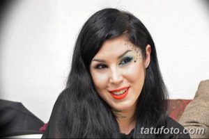 Портрет женщины с черными волосами и татуировками в виде звезд на лице и шее, демонстрирующей загадочный и привлекательный образ.