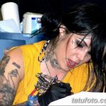 Фотография Kat Von D во время работы над татуировкой, с татуировками на руках и шее, в тату-салоне.