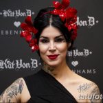Фотография Kat Von D с ярким макияжем и татуировками на руках и шее, на фоне черного баннера с логотипом Kat Von D Beauty.