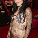 Фотография Kat Von D с татуировками на руках и животе, демонстрирующая ее привлекательную внешность.