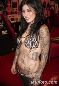 Фотография Kat Von D с татуировками на руках и животе, демонстрирующая ее привлекательную внешность.