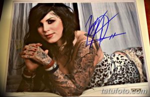 Фотография Kat Von D с автографом на фотографии, демонстрирующая ее татуировки на руках и теле.