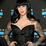 Фотография Kat Von D в черном платье с татуировками на руках, демонстрирующая ее яркий образ.