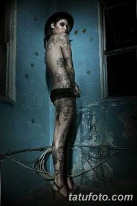 Фотография девушки с татуировками на спине и ногах, демонстрирующая сложный рисунок татуировки в темных тонах.