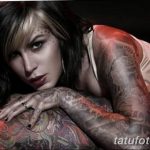 Фотография девушки с обширными татуировками на теле, демонстрирующая сложный рисунок татуировки в стиле традиционной американской татуировки и реализма.