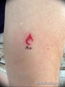 Фото тату: маленькая красная капля крови с надписью 'A+'. Простой и лаконичный рисунок татуировки, указывающий на группу крови.