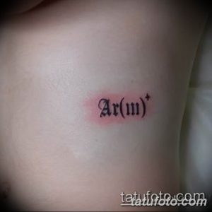 Фото тату с изображением химической формулы группы крови Ar(III)+, выполненной черными чернилами на светлой коже предплечья.