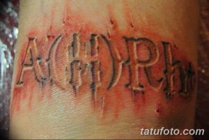 Фото тату: готическая татуировка 'A(II)Rh' с эффектом стекающей крови на руке. Черно-красный рисунок татуировки.