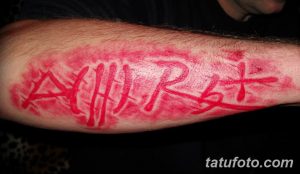 Фото тату: красная татуировка 'A(II)Rh+' с эффектом брызг на руке. Яркий и эффектный рисунок татуировки.