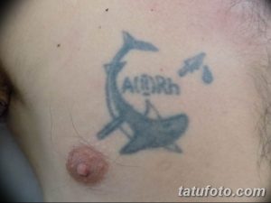 Фото тату: татуировка акулы с надписью 'A(II)Rh+' и капельками воды на груди. Рисунок татуировки выполнен в синих тонах.