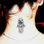 Фото татуировки Хамса (Рука Фатимы) на затылке. Черно-белый рисунок татуировки с синим глазом.