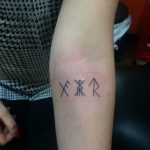 Фото минималистичной рунической татуировки на запястье. Черно-белый рисунок татуировки с тремя рунами.