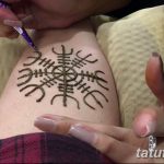Фото хна-тату рунического компаса на руке. Мастер наносит рисунок с помощью хны, демонстрируя процесс создания временной татуировки.