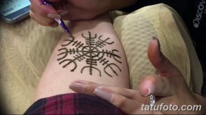 Фото хна-тату рунического компаса на руке. Мастер наносит рисунок с помощью хны, демонстрируя процесс создания временной татуировки.