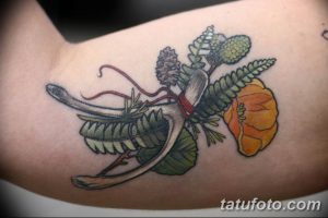 Необычная татуировка с изображением растений, кости и ленты, выполненная в ярких цветах на плече. Эскиз тату в ботаническом стиле.