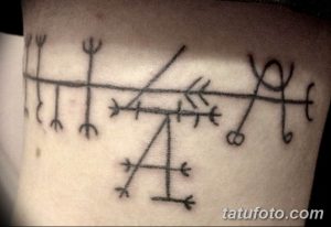 Фото татуировки в стиле blackwork, изображающей ряд древних рун, расположенных на руке. Мистический и загадочный рисунок татуировки.
