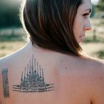 Фото тату Сак Янт на спине женщины. Черно-белый рисунок с геометрическими фигурами и тайскими письменами, выполненный в традиционном стиле.