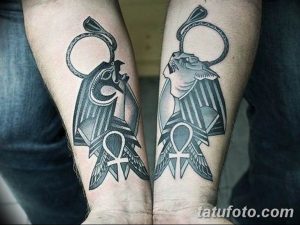 Фото двух татуировок Анубиса на предплечьях. Рисунки выполнены в черных тонах с использованием геометрических узоров и символа Анкх.