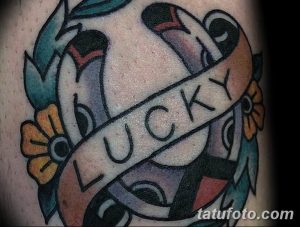 Фото татуировки: изображение сердца, пронзенного стрелой, с лентой и надписью "LUCKY". Традиционный олдскульный стиль.