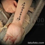Фото тату с иероглифами, расположенными вертикально на запястье, выполнено в черном цвете.